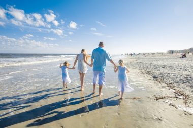 A family of four walks along the beach on Tybee Island, one of many beautiful small towns in Georgia.