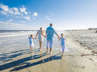 A family of four walks along the beach on Tybee Island, one of many beautiful small towns in Georgia.