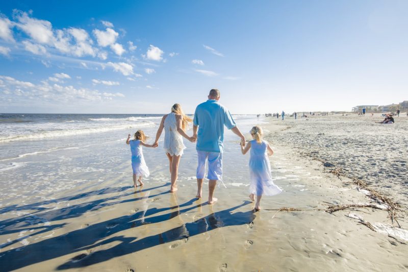 A family of four walks along the beach on Tybee Island, one of many beautiful small towns in Georgia.