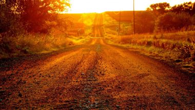 Sunset over a red gravel road.