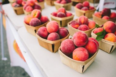 Summer peaches in baskets at a farmers market stand.