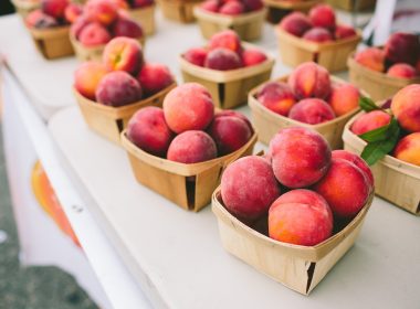 Summer peaches in baskets at a farmers market stand.