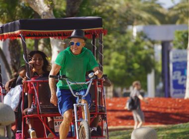 Happy pedicab driver and his passengers on a sunny day outside in the park.