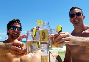Dude hanging out on the beach with mugs of beer