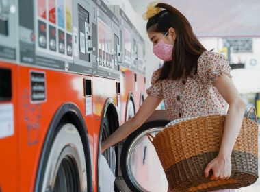 New normal lifestyle, Asian beautiful millennial woman washing her clothes in the automatic laundry self service