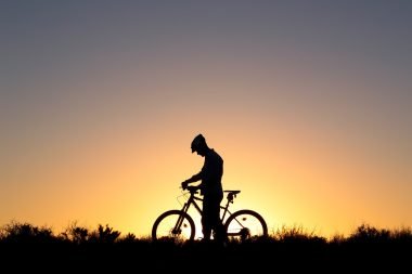 The silhouette of a bicyclist against a sunset