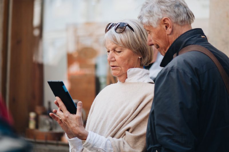 A senior couple traveling abroad and looking confused at their mobile device.