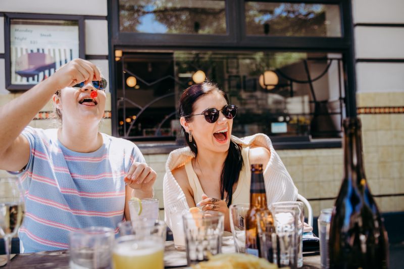 Millennials enjoy brunch and laugh while dining outside.