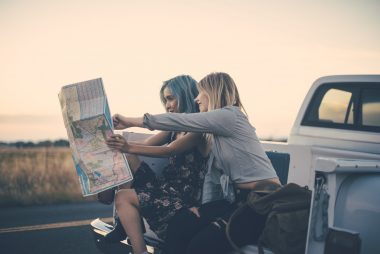 Two women traveling in a pickup plan their route using a map.
