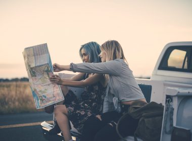 Two women traveling in a pickup plan their route using a map.