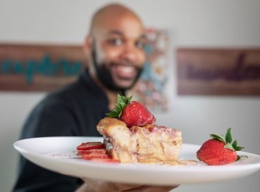 Cook holding up a plate of delicious cake and strawberries