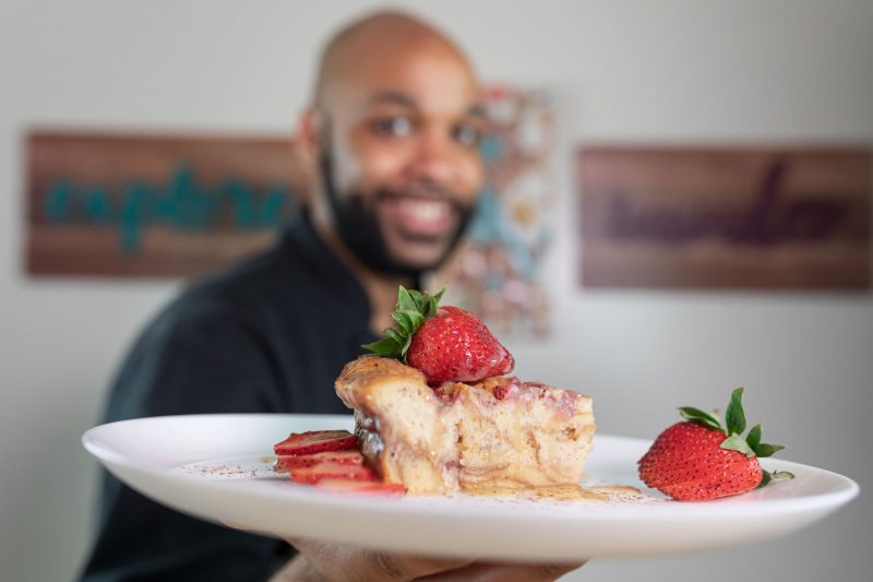Cook holding up a plate of delicious cake and strawberries