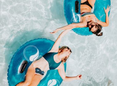 Two yougn women in bikinis floating in tubes on a lazy river in a water park.