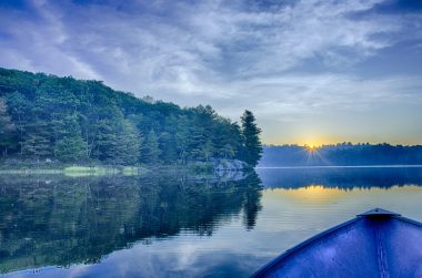 Sun rise over a blue lake from vantage point of a canoe