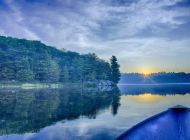 Sun rise over a blue lake from vantage point of a canoe