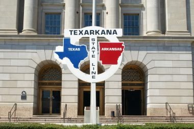 A sign for the state line of Texas and Arkansas running through the middle of the cities' federal building.