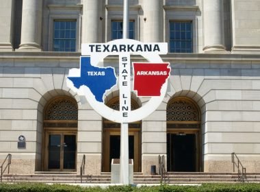 A sign for the state line of Texas and Arkansas running through the middle of the cities' federal building.