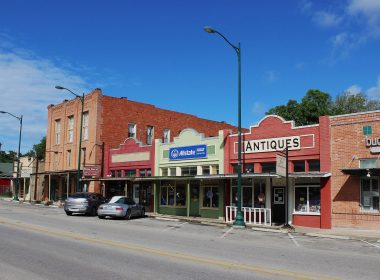 Shops along the street in historic downtown Buda, TX on a blue sky, sunny day.
