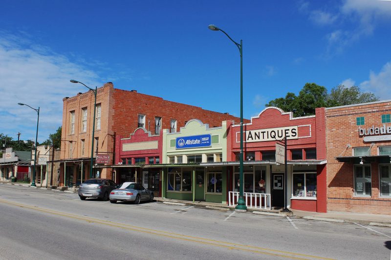Shops along the street in historic downtown Buda, TX on a blue sky, sunny day.