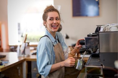 A happy barista makes a coffee latte at in shop