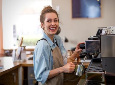 A happy barista makes a coffee latte at in shop