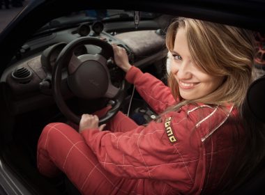A woman in a racing suit smiles and gets ready to rally race.