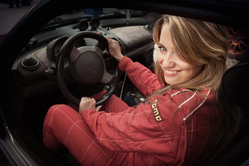 A woman in a racing suit smiles and gets ready to rally race.