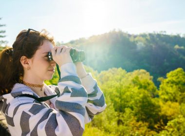 A young hiker looks through her binoculars while standing on high ground in Cherokee National Forest in Tennessee (TN).
