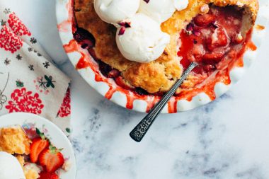 Top down view of a berry pie with a spoon and whipped topping.