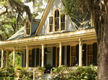 Southern plantation home with spanish moss and trees surrounding the front porch.