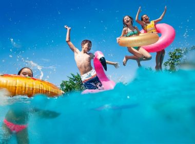 Young teenagers jumping into a lake with inner tubes.
