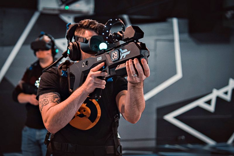 A man wears a virtual reality headset and holding a gaming gun in a Zero Latency gameroom.
