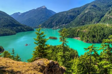 Diablo Lake in Washington shines bright turquoise in the sun, surrounded by mountains.