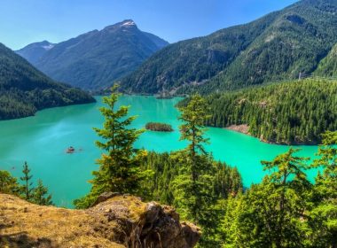 Diablo Lake in Washington shines bright turquoise in the sun, surrounded by mountains.