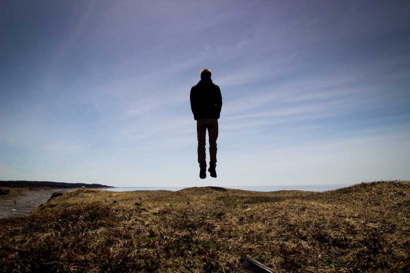 A man floating out in nature against the sky.