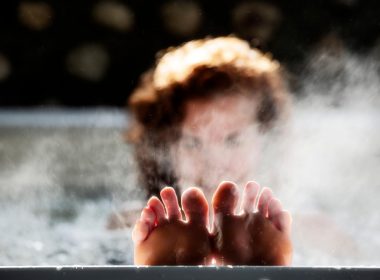 A woman relaxes in a heated soaking pool with her feet up on the edge.