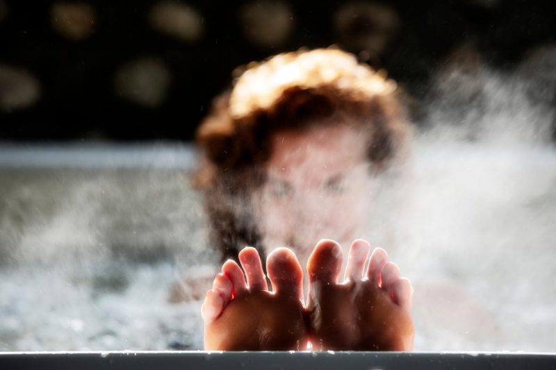 A woman relaxes in a heated soaking pool with her feet up on the edge.