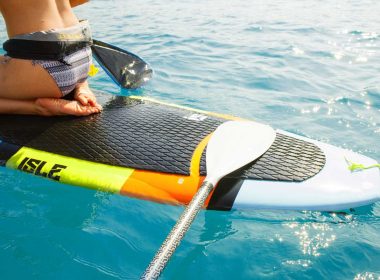 A paddle resting on a paddle board in aquamarine waters