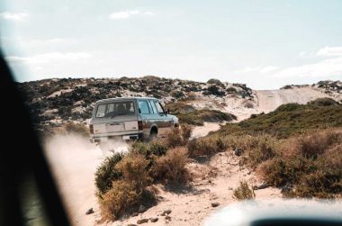 A 4x4 vehicle travels down a dirt road off roading in the desert.