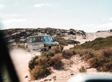 A 4x4 vehicle travels down a dirt road off roading in the desert.