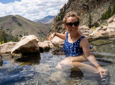 A woman in a patriotic swim suit soaks in the hot springs with a beautiful view over the mountains in Idaho.