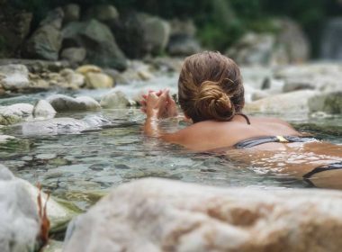 A woman floats on her stomach and relaxes in the water of a natural hot spring.