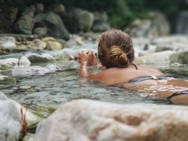 A woman floats on her stomach and relaxes in the water of a natural hot spring.