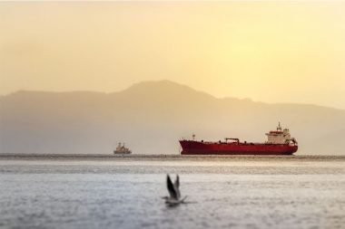 A red tanker ship off the coast of Alaska at sunset in the Bering Sea between Alaska and Russia.