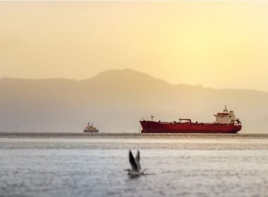 A red tanker ship off the coast of Alaska at sunset in the Bering Sea between Alaska and Russia.