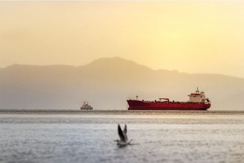 A red tanker ship off the coast of Alaska at sunset in the Bering Sea between Alaska and Russia.