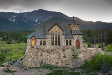 The historic St. Malo, also called Chapel on the Rock, on a summer evening with lights beginning to glow from the inside of the chapel.