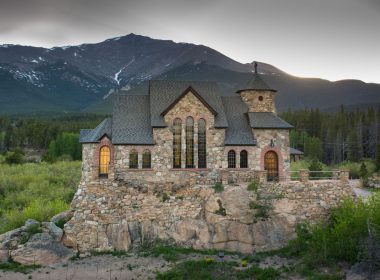 The historic St. Malo, also called Chapel on the Rock, on a summer evening with lights beginning to glow from the inside of the chapel.