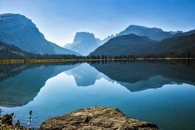 A glassy Green River reflecting the sky and mountain landscape in Wyoming.