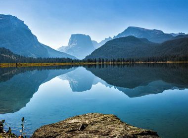 A glassy Green River reflecting the sky and mountain landscape in Wyoming.